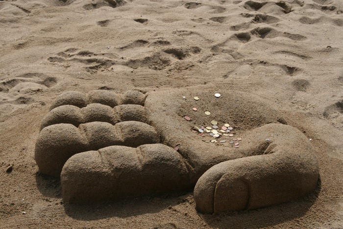 Sand sculpture of a hand with coins