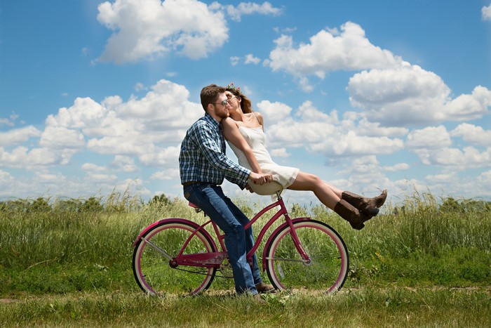 Couple kissing on a bicycle in a field
