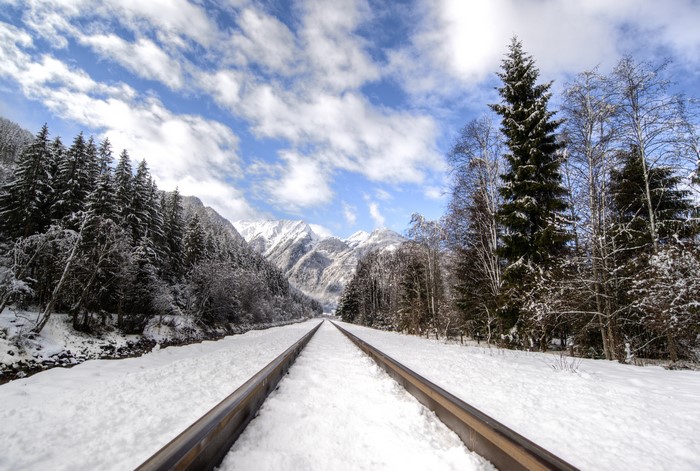 Railroad tracks covered in snow leading to mountains