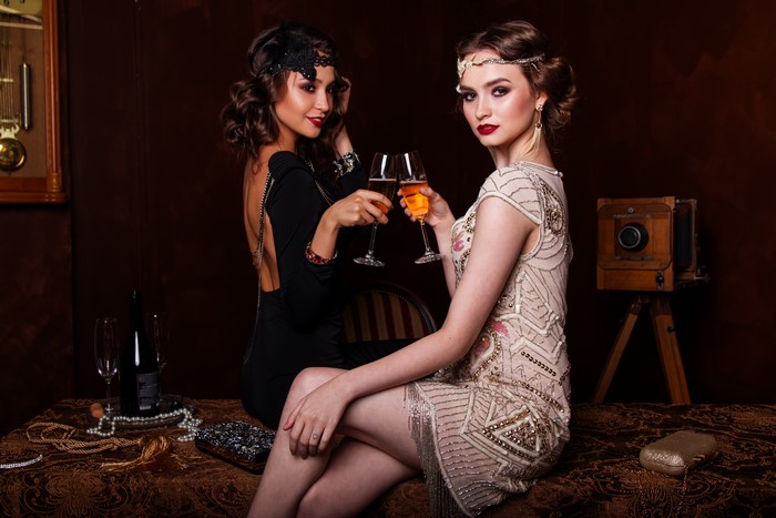 Two women in retro dresses toasting with champagne