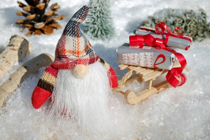 Christmas gnome with gifts on a sled in the snow