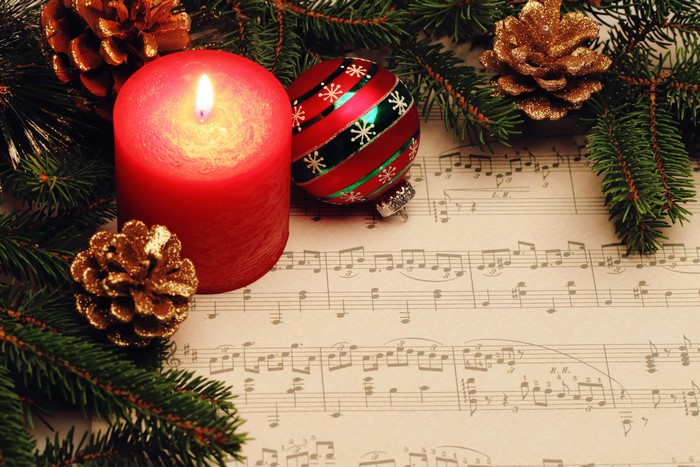 Christmas candle, ornament, pine cones on sheet music