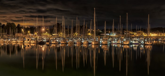 Sailboats docked in a marina at night with reflections