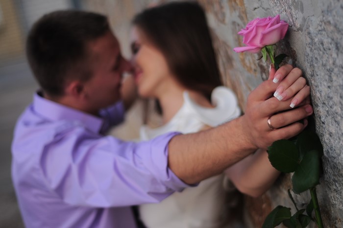 Couple kissing with a pink rose