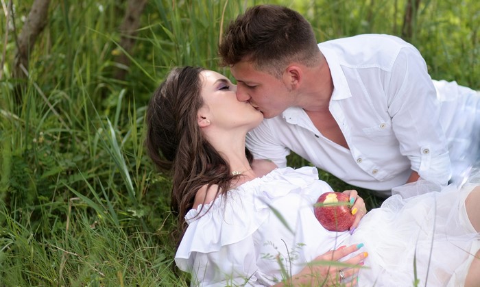 Couple kissing in grass with apple