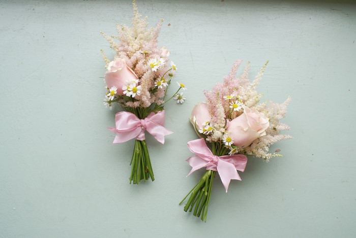 Two pink rose bouquets with astilbe and daisies tied with pink bows