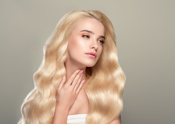 Blonde woman with wavy hair and hands on neck