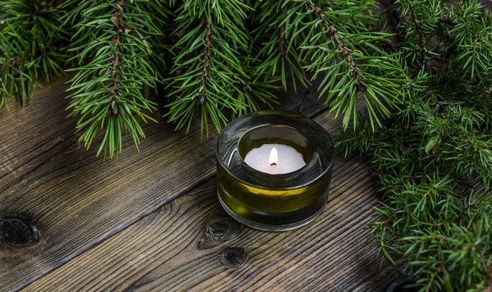 Candle with pine branches on wooden planks