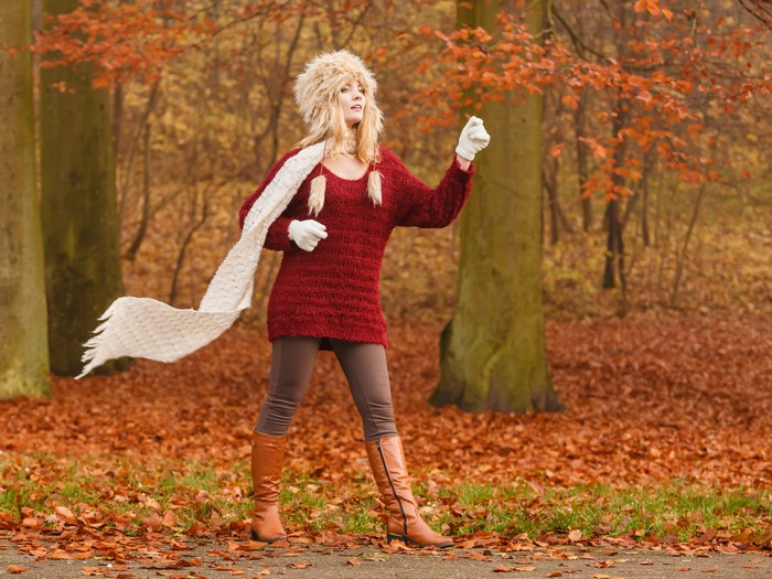 Woman in autumn forest wearing winter hat and scarf