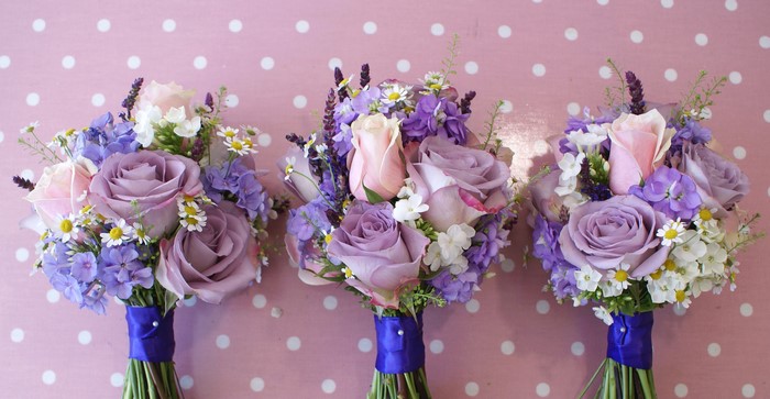 Three bouquets of purple roses and wildflowers