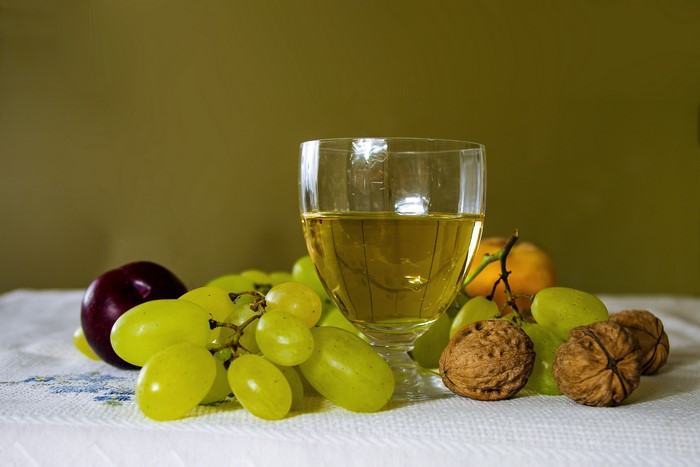 Still life with grapes, wine, plum, walnuts, and orange