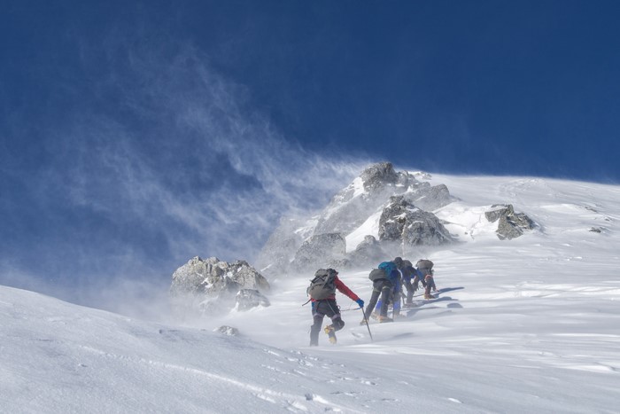 Mountaineers climbing a snowy mountain in strong winds
