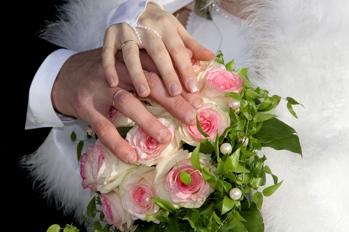 Wedding rings on hands over a bouquet