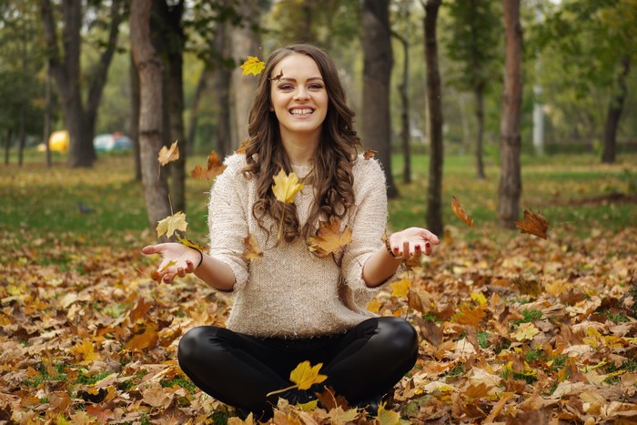 Woman in sweater sitting in autumn foliage