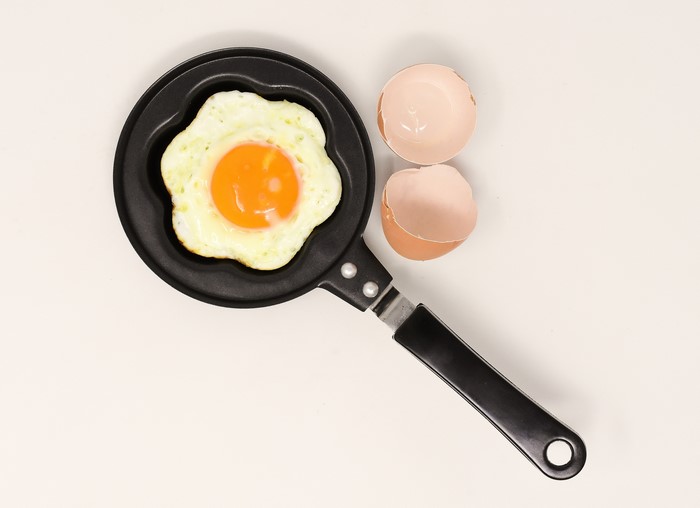 Fried egg in a flower-shaped frying pan with eggshells