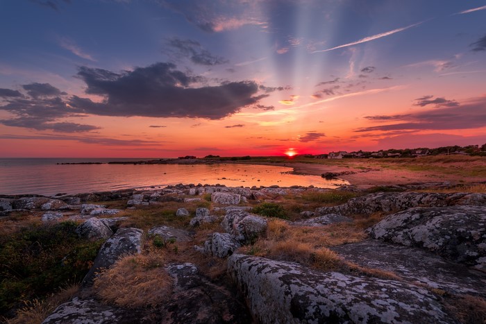Sunset over rocky coast with sun rays