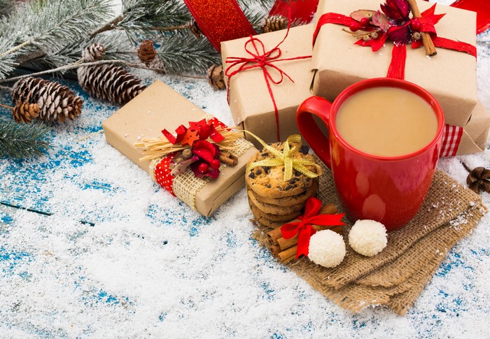Christmas gifts, coffee, cookies, and pine cones in snow