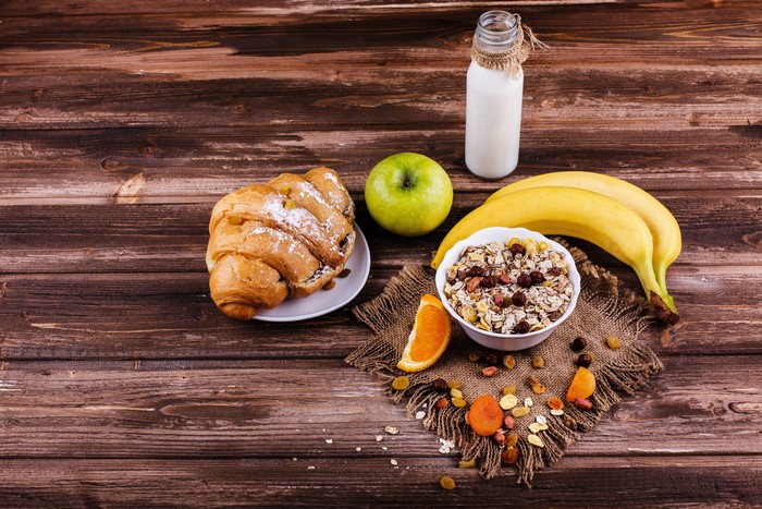 Breakfast with Croissant, Muesli, Bananas, Apple, and Milk
