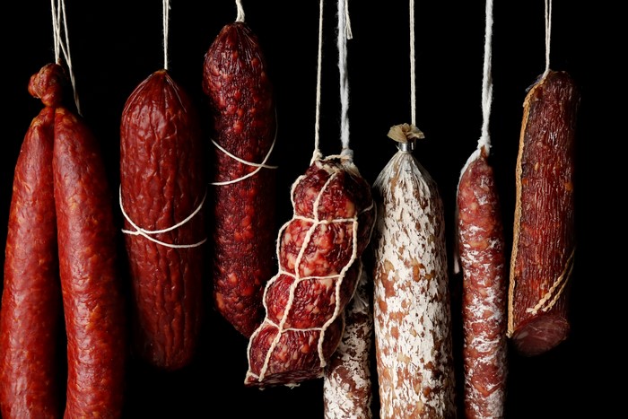 Various sausages hanging on black background