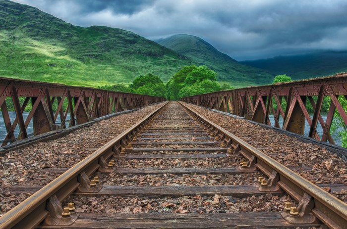Railroad bridge over water with mountains