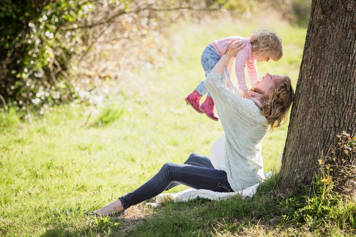 Pregnant Woman Holding Daughter by Tree