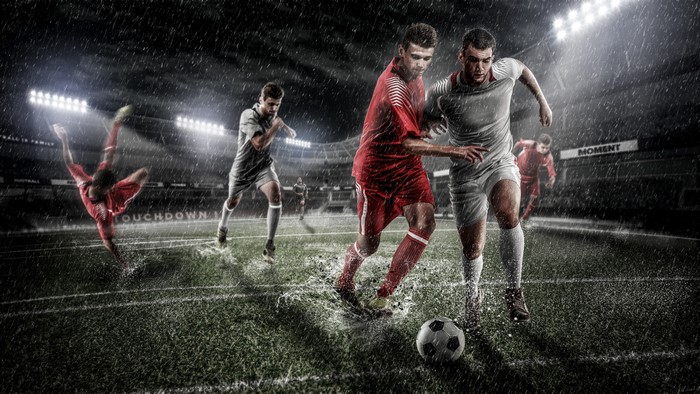 Soccer players in a rainy stadium