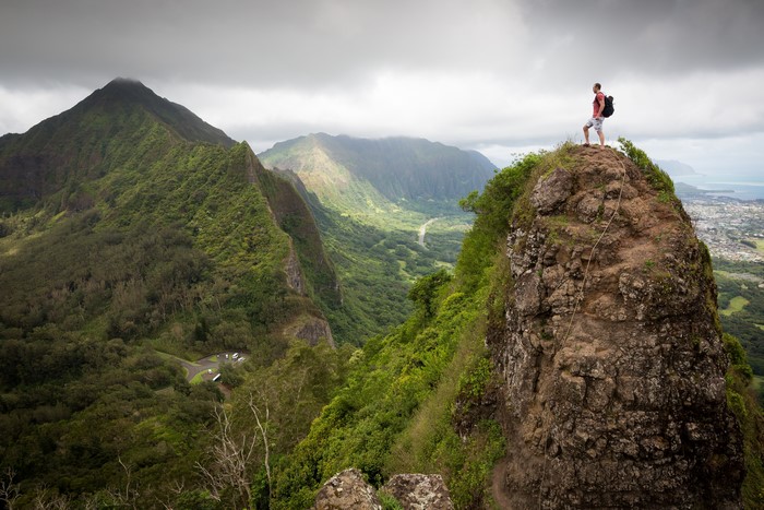 Man on a mountain peak overlooking a valley