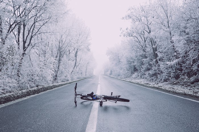 Bicycle lying on a wet road in winter forest