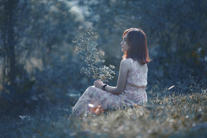 Asian woman with brown hair sitting in grass