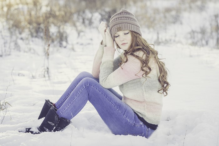 Girl in Winter Hat and Sweater Sitting in Snow