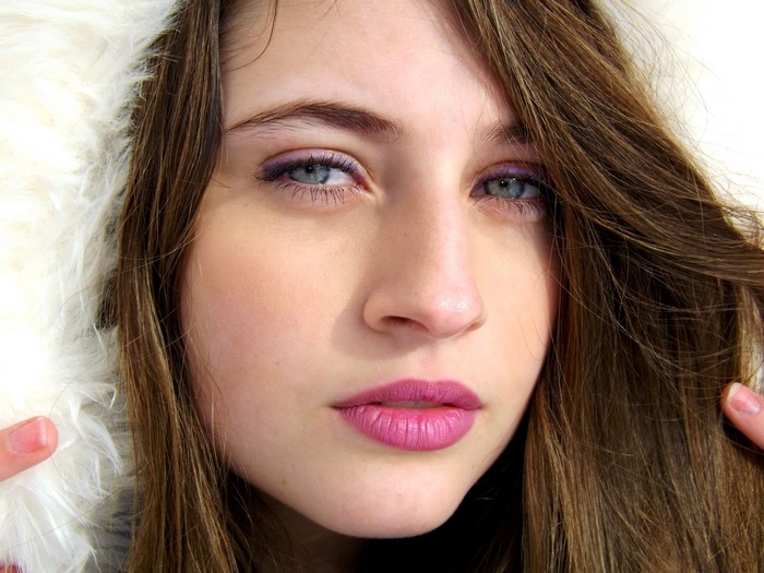 Close-up of a young woman with brown hair and purple eyeshadow