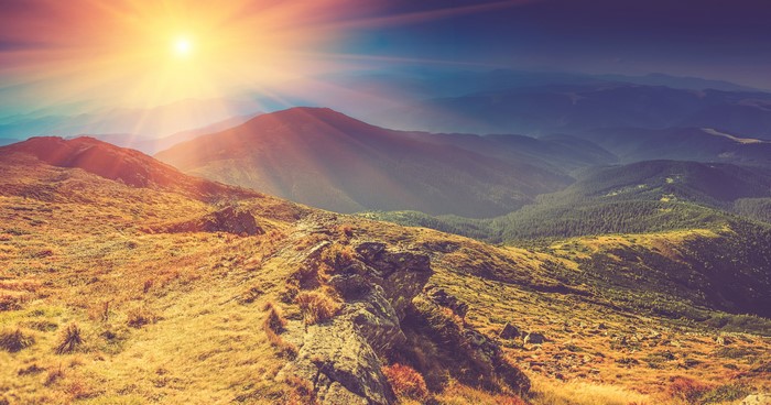 Sunlight over mountains and grassy hills