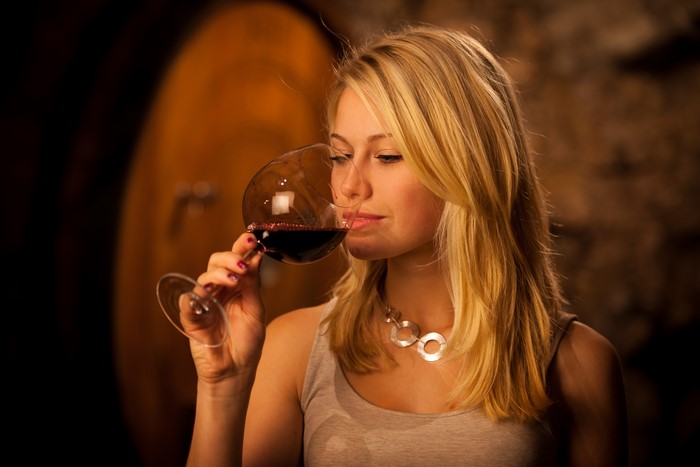 Blonde girl drinking red wine from a glass