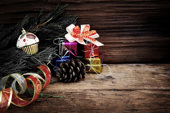 Christmas ornaments, gifts, and pine cone on wood
