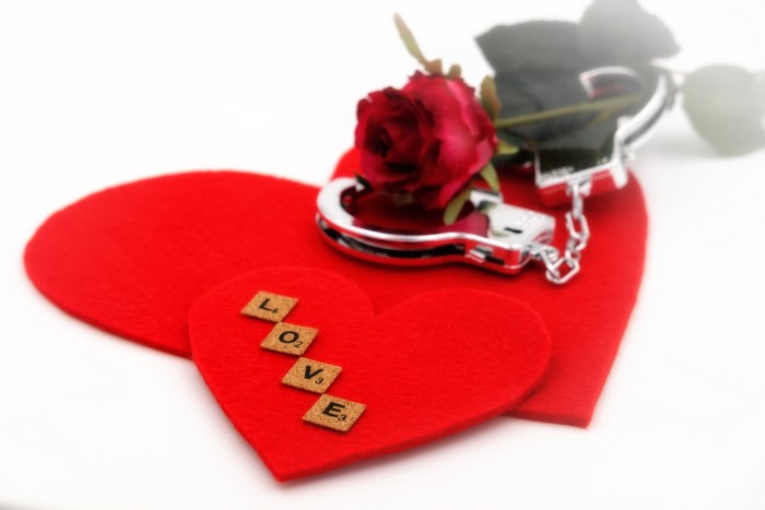 Love handcuffs and rose on red hearts