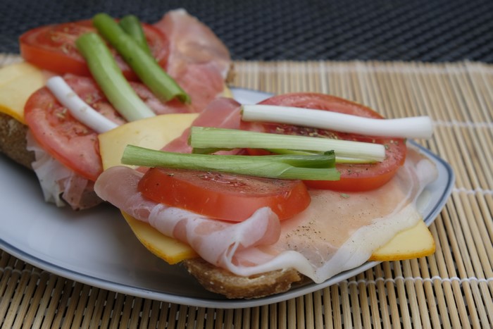 Ham, cheese, and tomato sandwiches with green onions on a plate