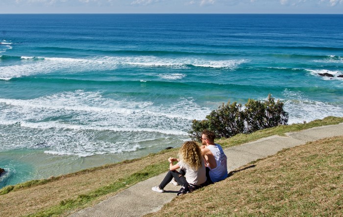 Couple Sitting on a Grassy Hill Overlooking the Ocean