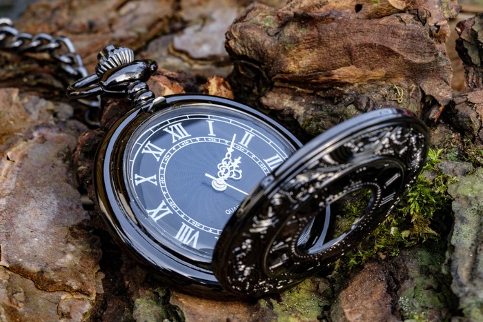Black pocket watch on textured wood