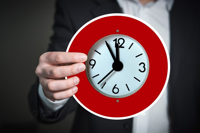 Man in Suit Holding a Red Clock