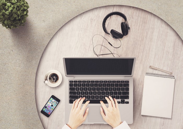 Overhead view of person typing on laptop with coffee and headphones