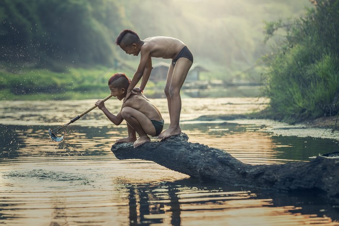 Two Asian boys fishing in a river