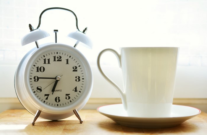 Alarm clock and coffee mug on a wooden surface