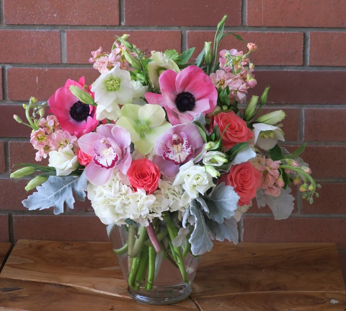 Pink and white floral arrangement with orchids and roses