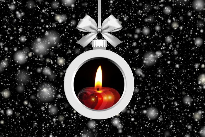 Christmas ornament with candle and bow on snowy background