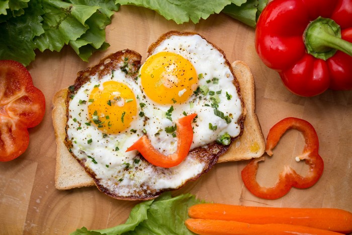 Fried eggs on toast with bell peppers and lettuce