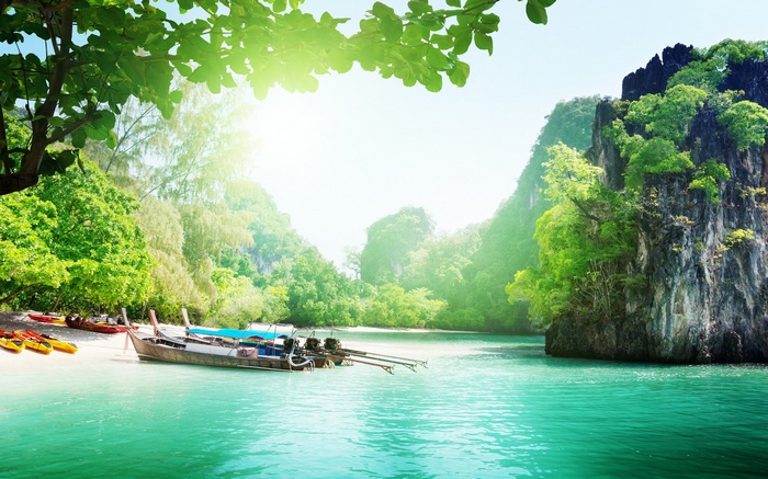 Longtail boats on a tropical beach with limestone cliffs