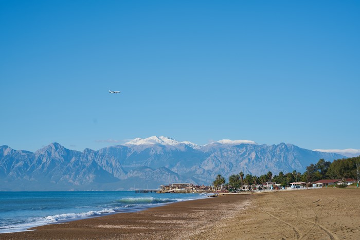 Airplane flying over beach with mountains in Antalya, Turkey