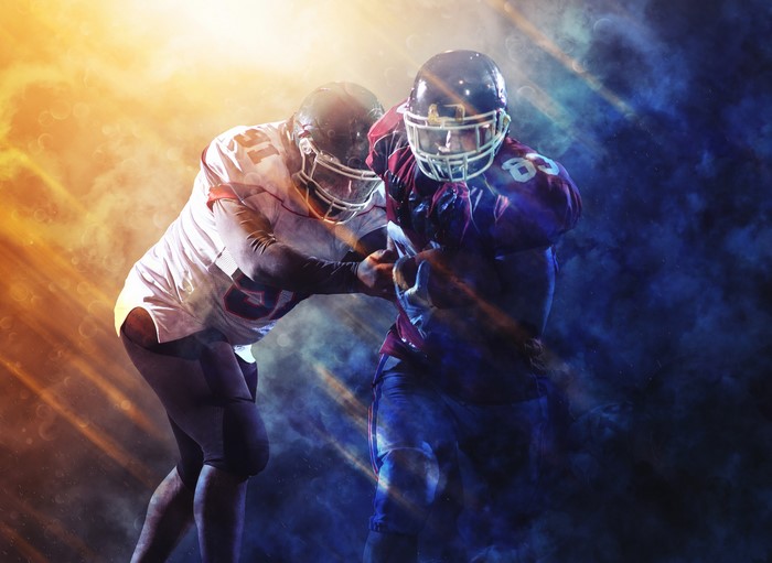 Two American football players in uniform and helmets