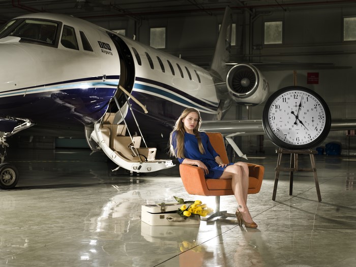 Woman sitting in armchair next to airplane and clock
