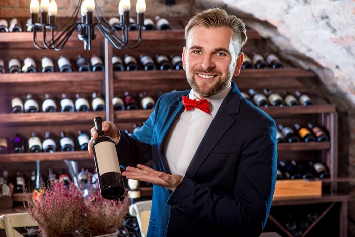 Man in Suit Holding Wine Bottle in Cellar